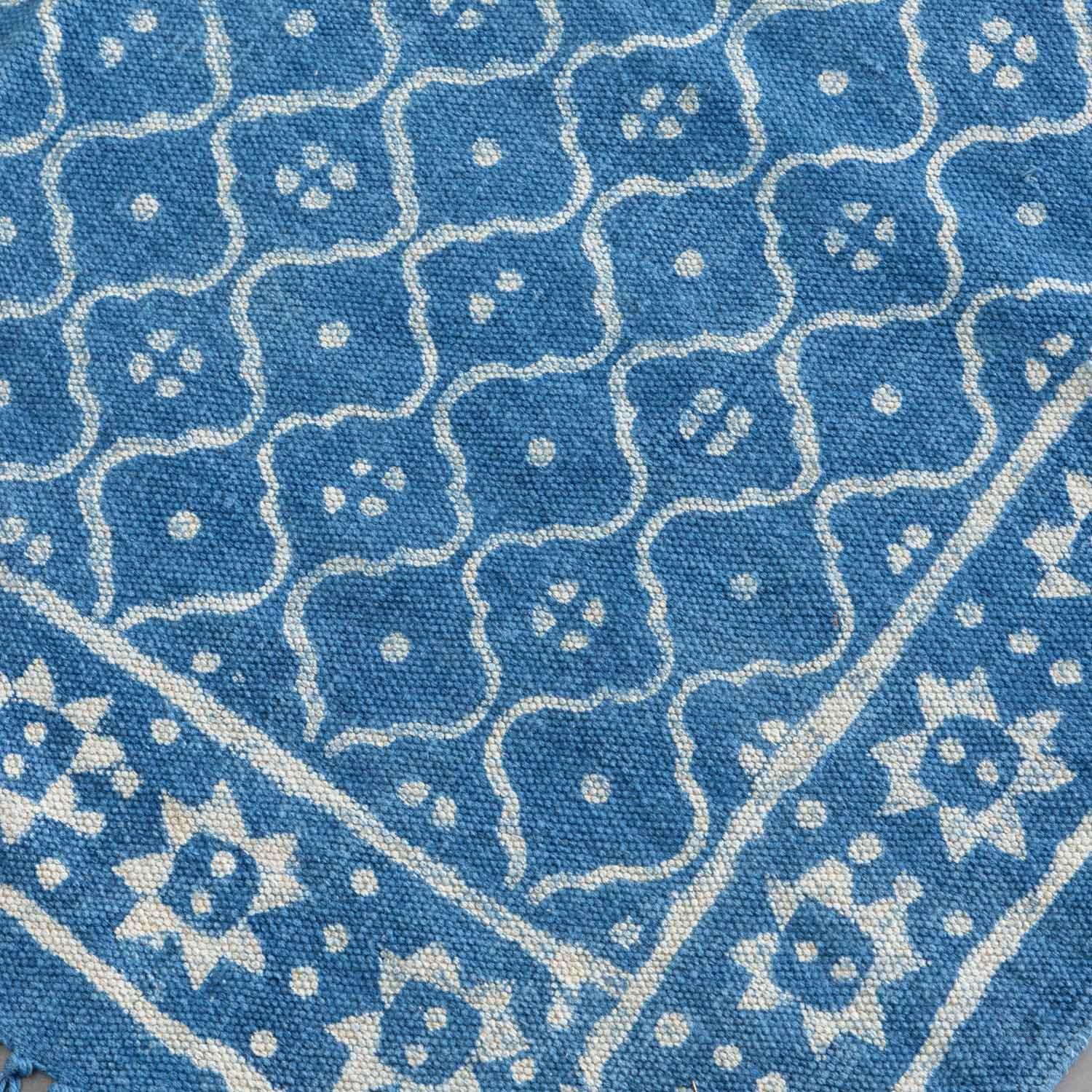 Close-up of geometric hand block printed patterns on an indigo cotton dhurrie, highlighting artisan craftsmanship
