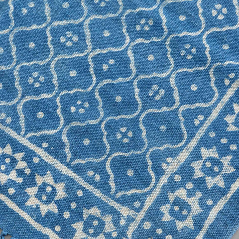 Close-up of geometric hand block printed patterns on an indigo cotton dhurrie, highlighting artisan craftsmanship