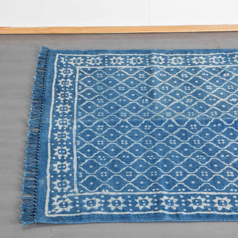 Top view of an indigo geometric hand block printed cotton rug, highlighting woven fringe and pattern detailing