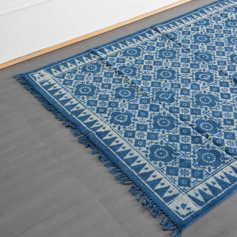 Oblique high-angle view of an indigo geometric floral block printed dhurrie rug showcasing pattern placement and craftsmanship