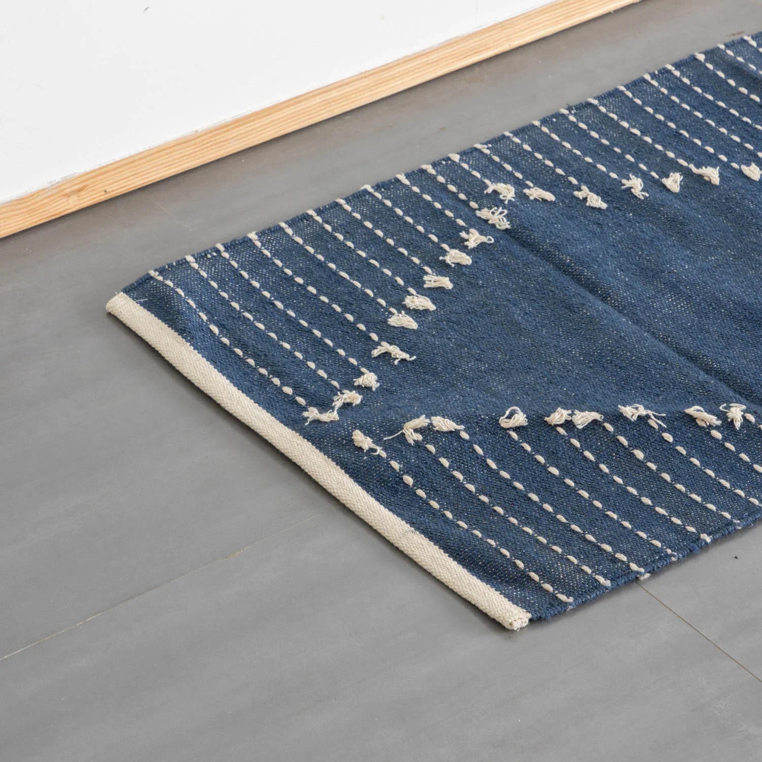 Oblique high-angle view of an indigo stripe handwoven cotton rug showcasing pattern placement and artisanal craftsmanship