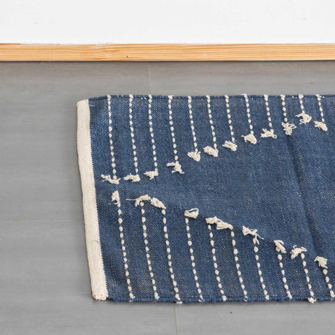 Top view of an indigo blue cotton dhurrie rug, highlighting handwoven white dotted stripes and weave detailing