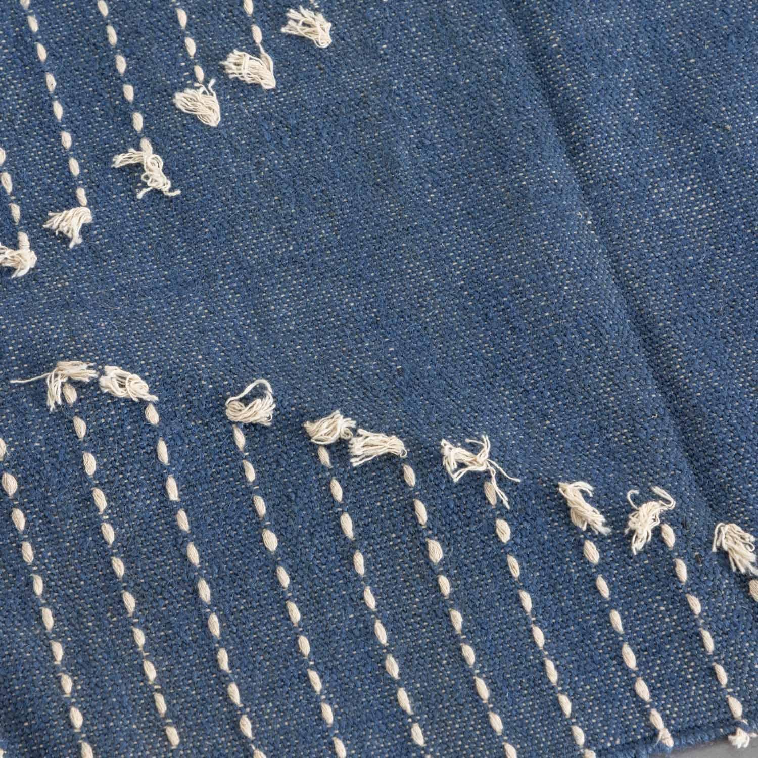 Close-up of handwoven white dotted stripe patterns on an indigo cotton dhurrie rug highlighting artisan craftsmanship