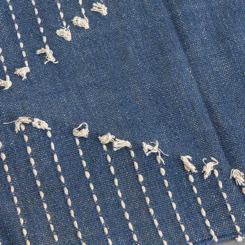 Close-up of handwoven white dotted stripe patterns on an indigo cotton dhurrie rug highlighting artisan craftsmanship