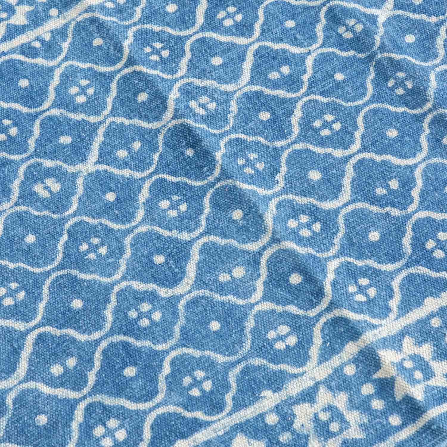 Close-up of trellis hand block printed motifs on an indigo cotton dhurrie highlighting artisan craftsmanship and texture