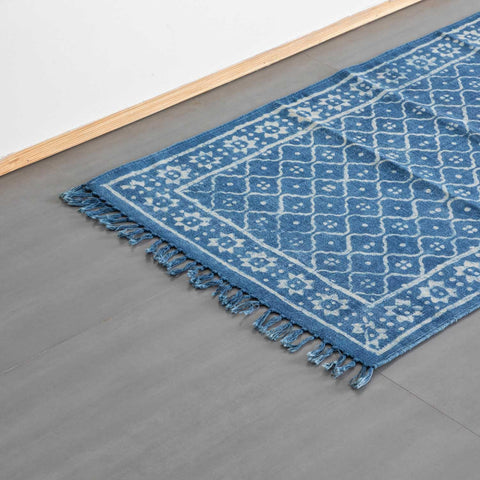 Oblique high-angle view of an indigo trellis block printed dhurrie rug showcasing trellis pattern placement and craftsmanship