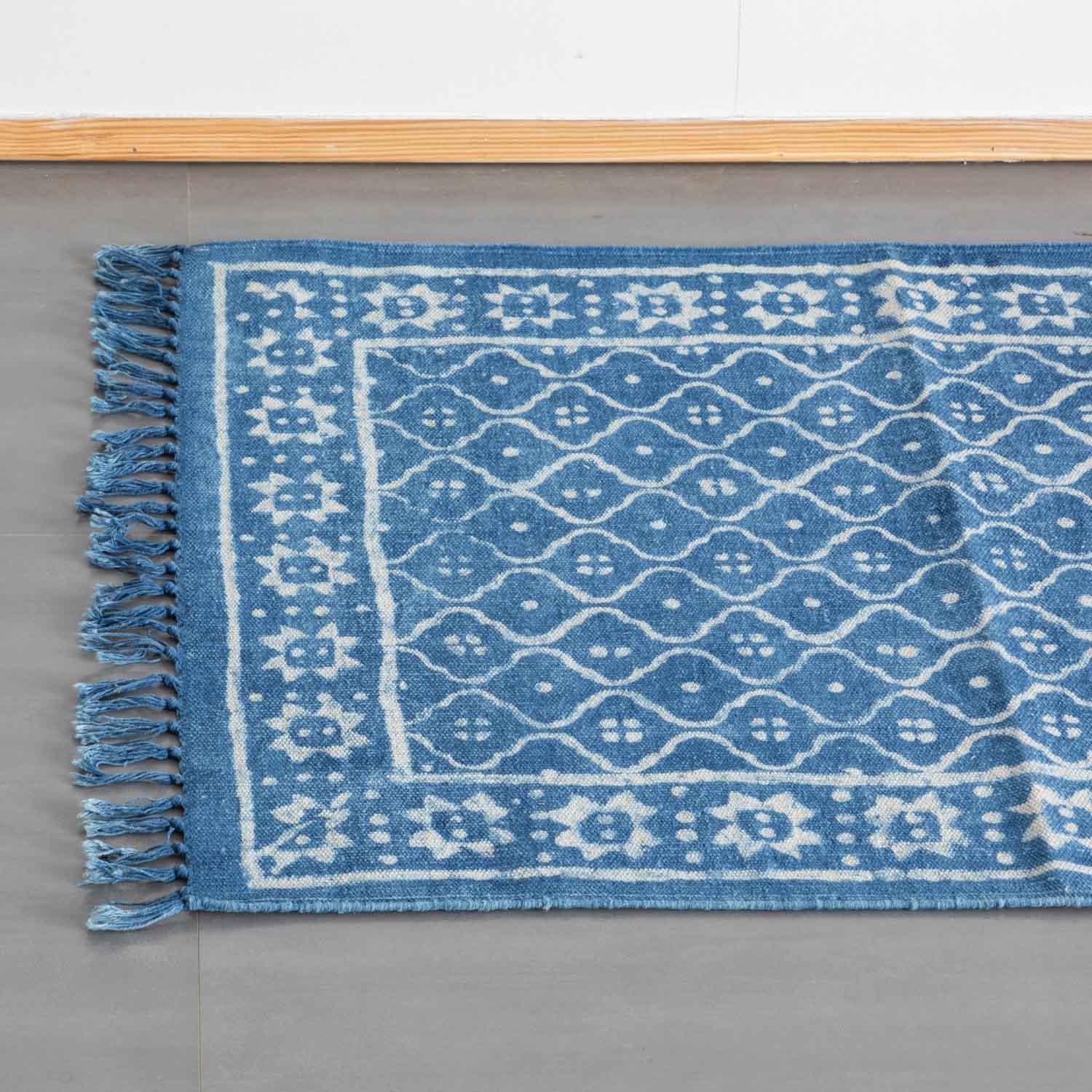 Top view of an indigo cotton dhurrie rug highlighting trellis block printed motifs and woven fringe detailing