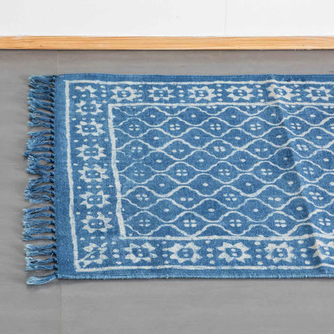 Top view of an indigo cotton dhurrie rug highlighting trellis block printed motifs and woven fringe detailing
