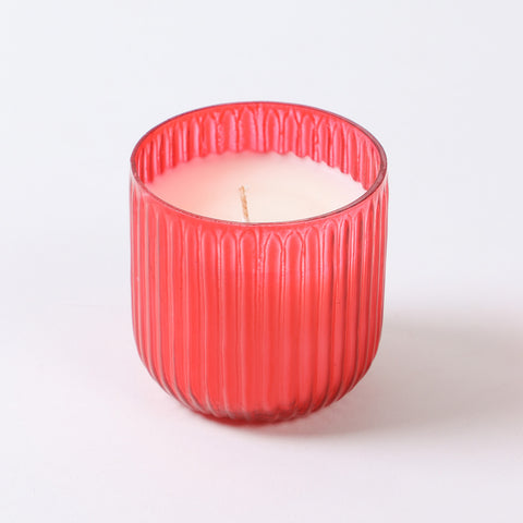 Red scented soy candle in a ribbed glass holder with apple cinnamon aroma