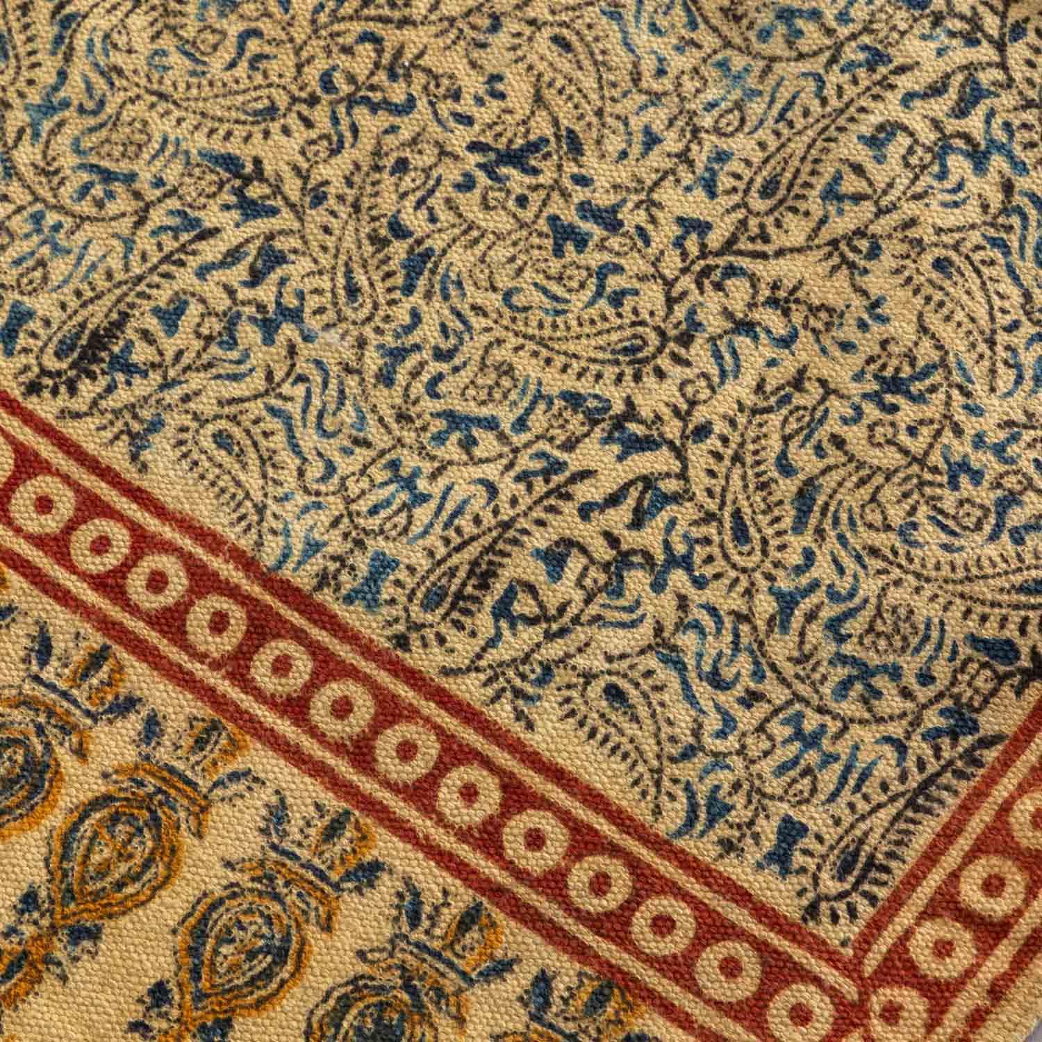 Close-up of Kalamkari-inspired hand block printed motifs on a mustard cotton dhurrie, highlighting artisan craftsmanship