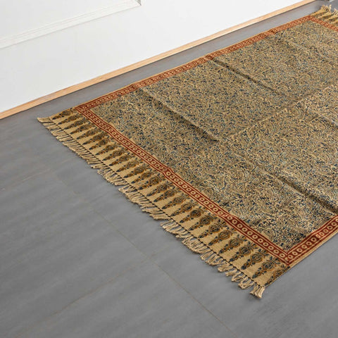 Oblique high-angle view of a mustard Kalamkari block-printed dhurrie rug showcasing pattern placement and craftsmanship