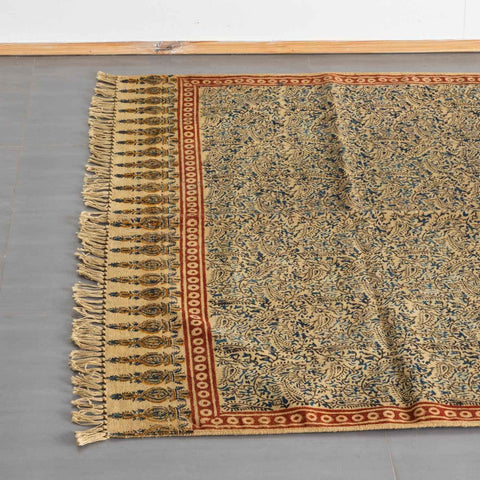 Top view of a mustard cotton dhurrie rug highlighting Kalamkari block prints and woven fringe detailing