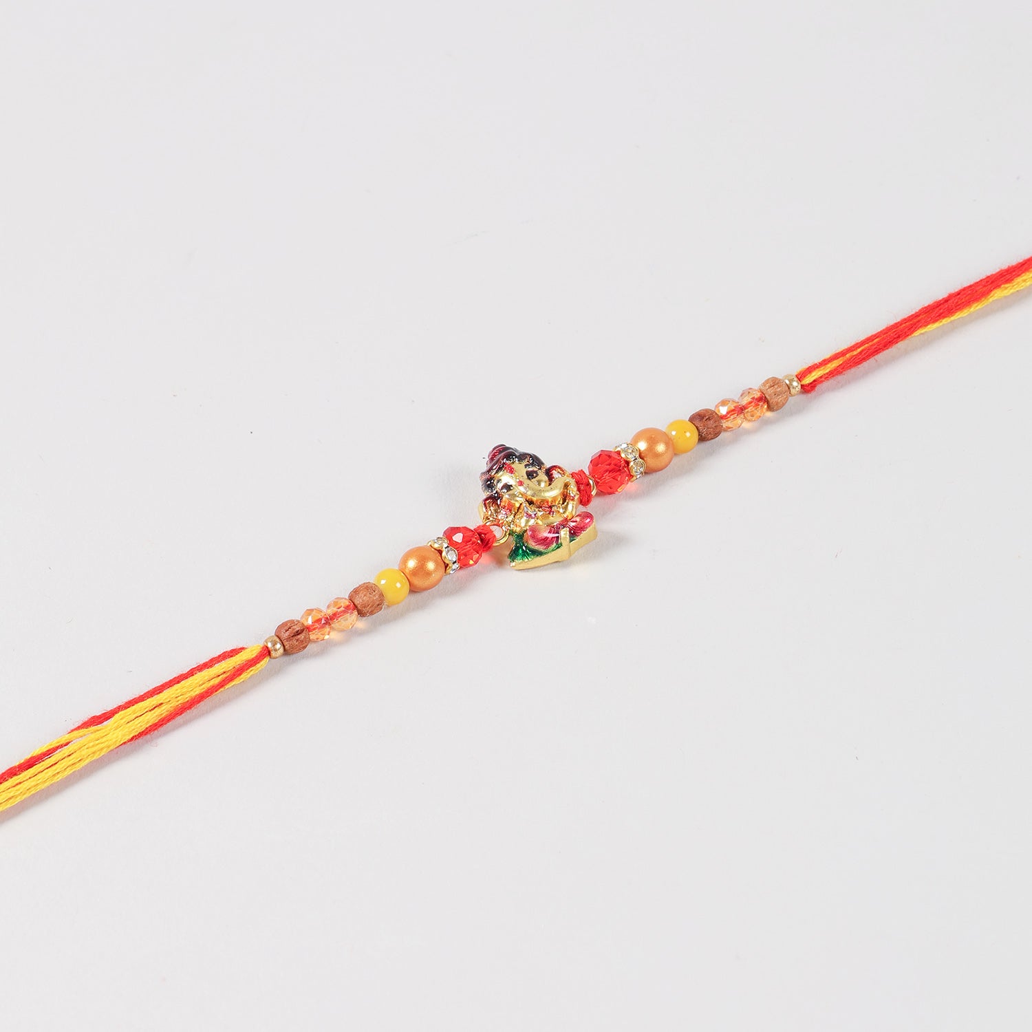 Close-up of the Handmade Kids Metal Ganesh Rakhi featuring the Bal Ganesh charm, crystal beads, gold-toned metal beads, and colourful thread