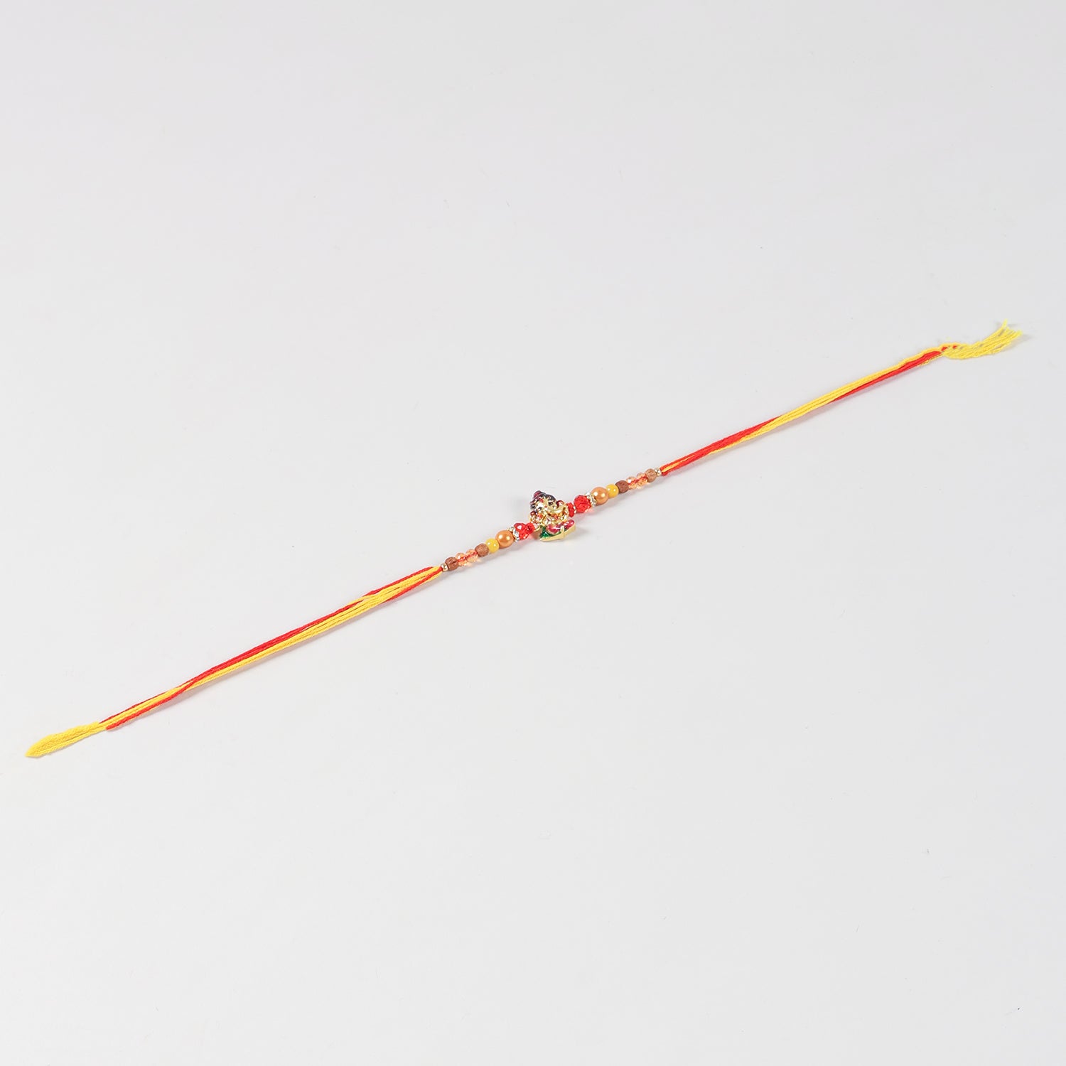 Full-length view of the Handmade Kids Metal Ganesh Rakhi, showcasing the handcrafted design and festive thread.
