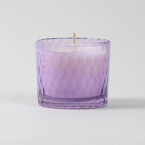 Eye-level view of a lavender scented soy wax candle showcasing the chiseled glass texture and purple finish