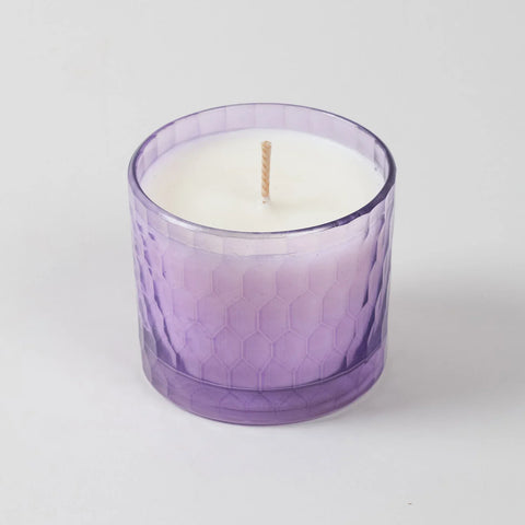 Front view of a lavender scented soy wax candle in a purple chiseled glass holder