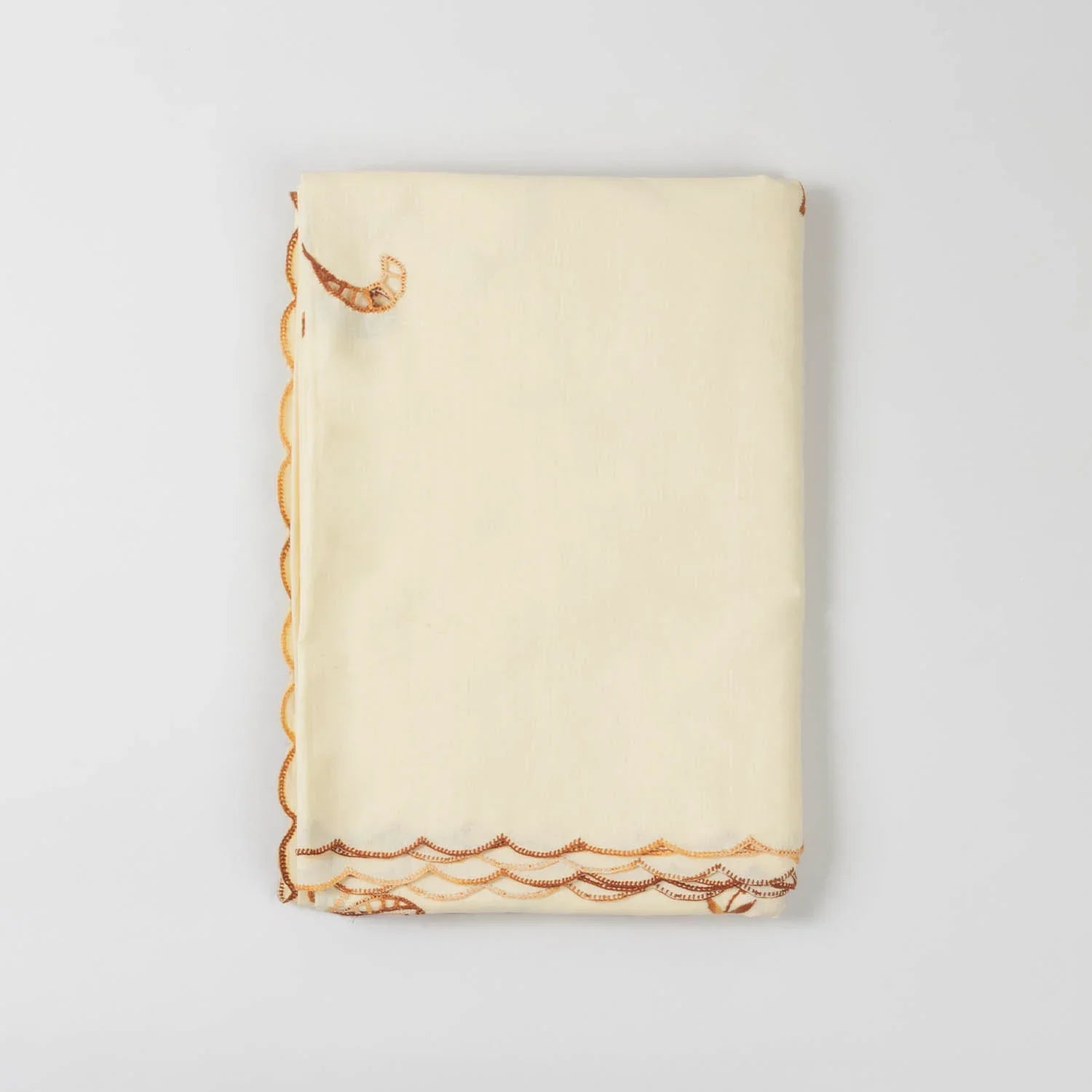 Folded view of a light brown embroidered bedcover set showcasing cotton fabric quality