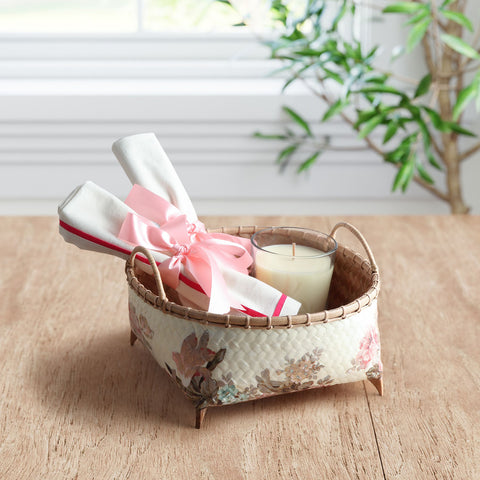 Handmade wicker storage basket with pink floral decoupage artwork holding home accessories on a table, ideal for gifting and organisation