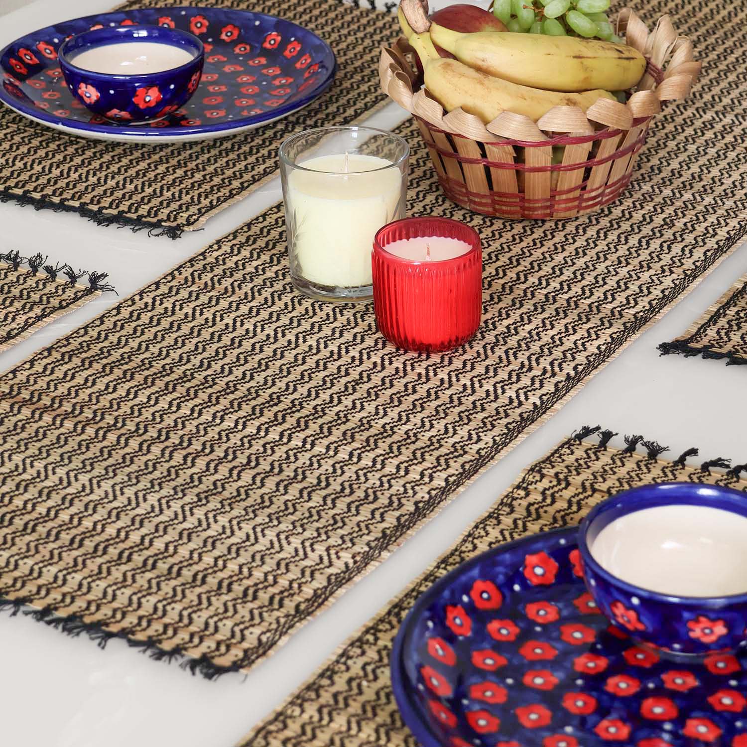 Dining table setting with a Madurkathi table runner and placemats set featuring natural river grass weave, black zigzag patterns, and handcrafted table decor