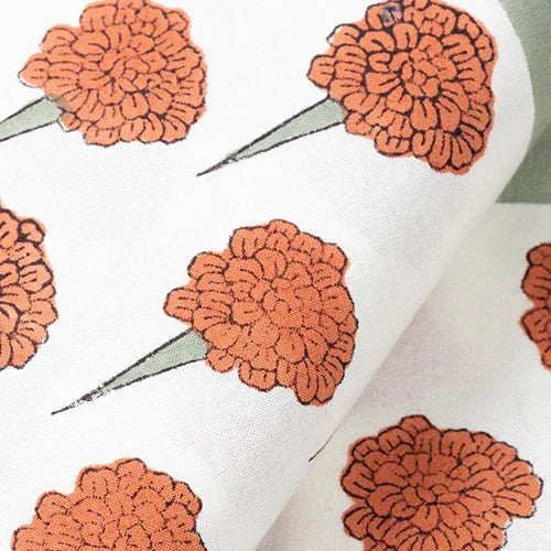 Close-up of orange marigold buti hand block printed motifs on a 100 percent cotton bedcover