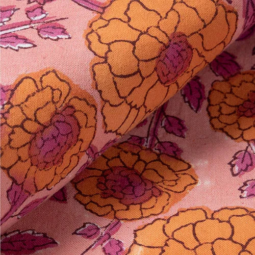 Close-up of orange and dark pink marigold jaal block printed motifs on a soft pink cotton bedcover
