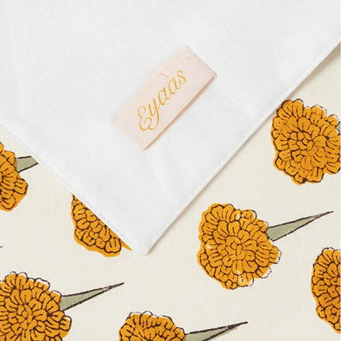 Front and reverse view of marigold floral block printed placemats with Eyaas brand tag and handcrafted detailing