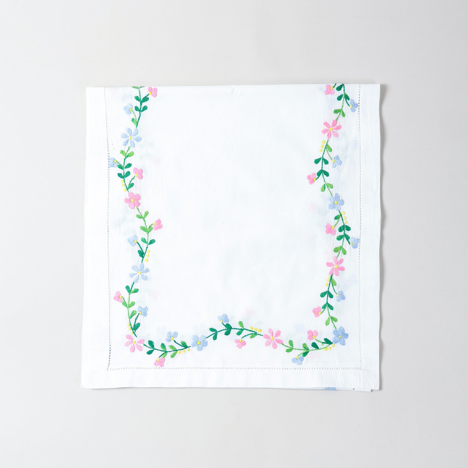 Folded white cotton table runner showcasing colourful floral vine embroidery and handcrafted Bengal chikankari detailing