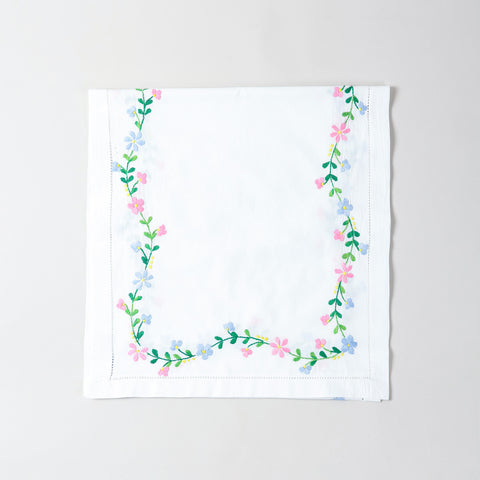 Folded white cotton table runner showcasing colourful floral vine embroidery and handcrafted Bengal chikankari detailing