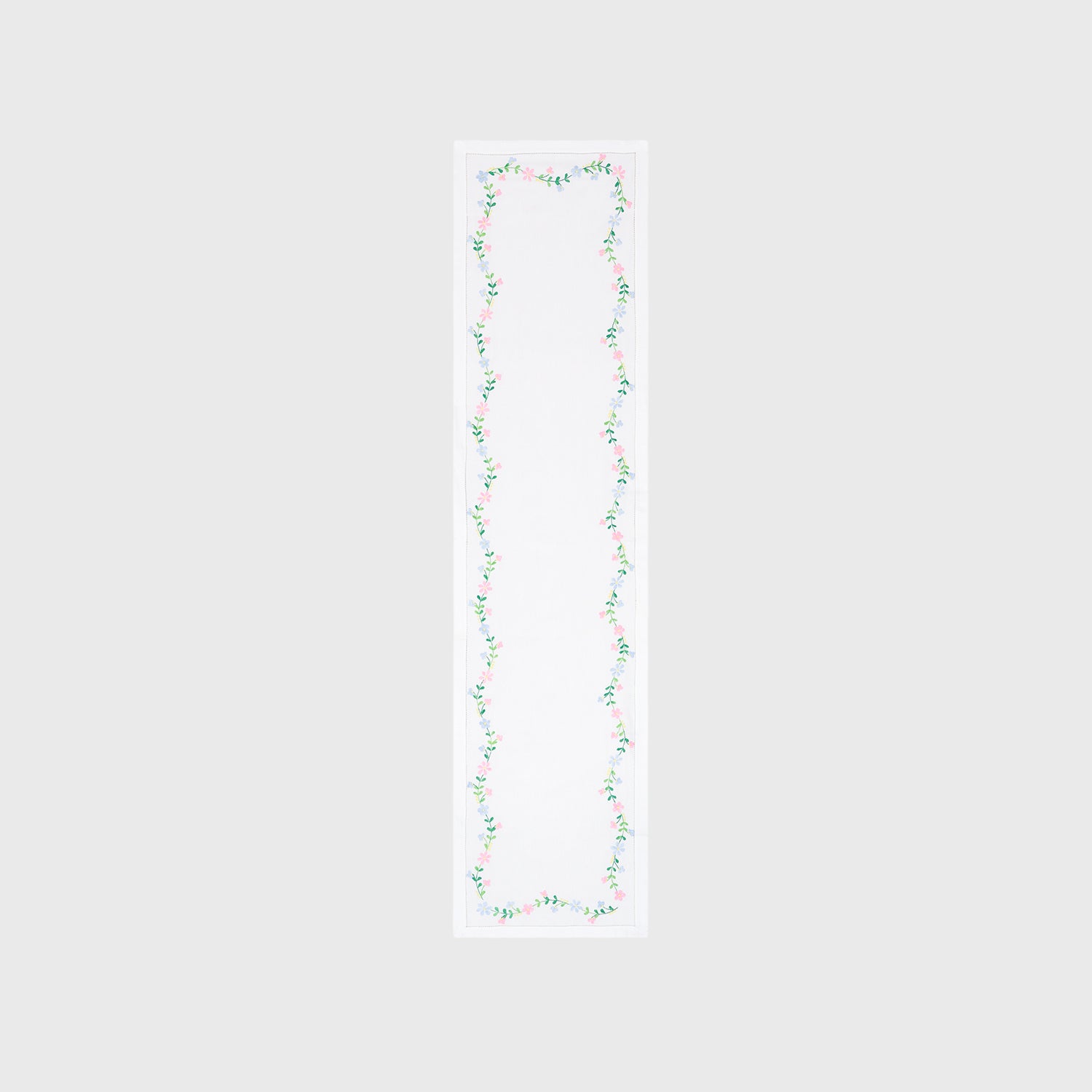 Full-length embroidered table runner featuring multicoloured floral vine motifs on a white cotton base displayed on a plain background
