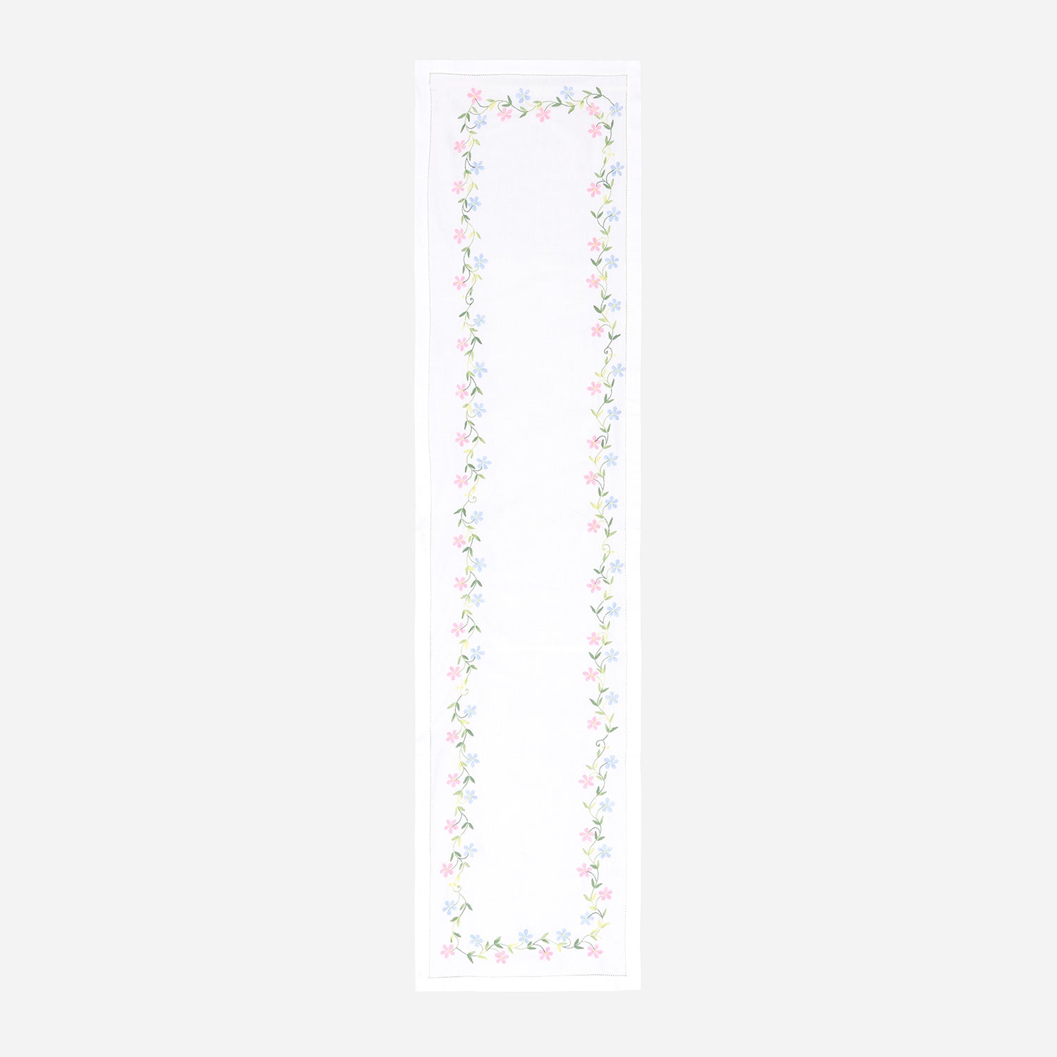 Full-length embroidered table runner featuring multicoloured daisy motifs on a white cotton base displayed on a plain background