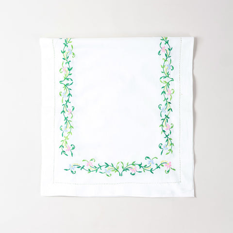 Folded Bengal chikankari runner showcasing multicoloured floral embroidery on soft white cotton table linen