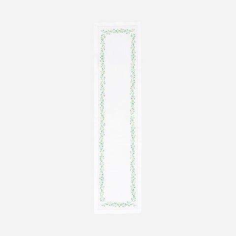 Full-length embroidered table runner featuring colourful floral vine motifs on a white cotton base displayed on a plain background