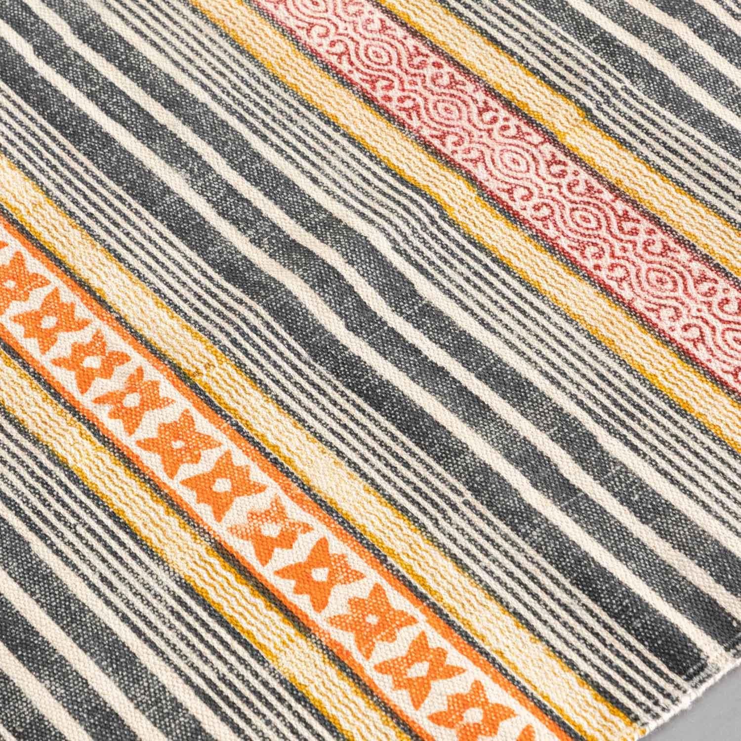 Close-up of geometric stripe hand block printed motifs on a multicolor cotton dhurrie highlighting artisan craftsmanship and texture