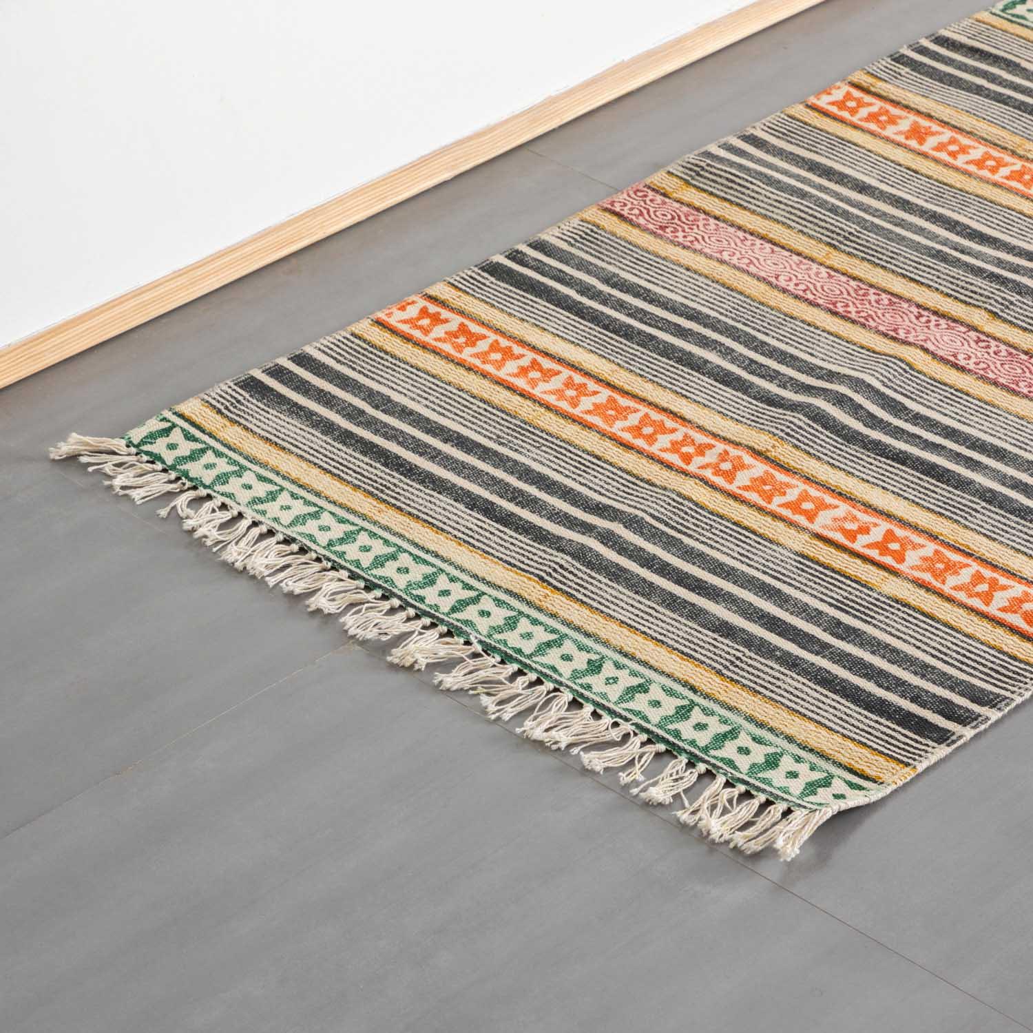 Oblique high-angle view of a multicolor geometric stripe block printed dhurrie rug showcasing pattern placement and craftsmanship