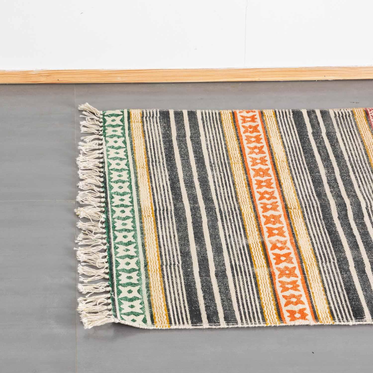 Top view of a multicolor cotton dhurrie rug highlighting geometric stripe block prints and woven fringe detailing