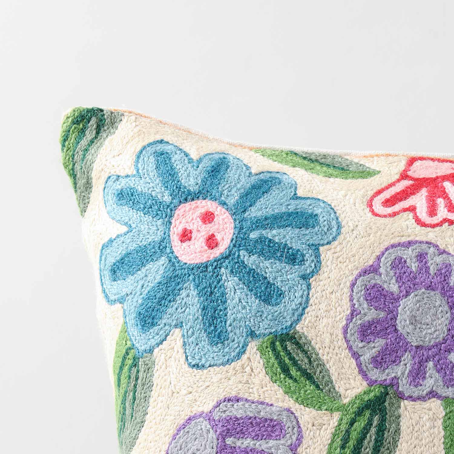 Close-up of colourful floral crewel embroidery highlighting textured wool threads and intricate handcrafted detailing