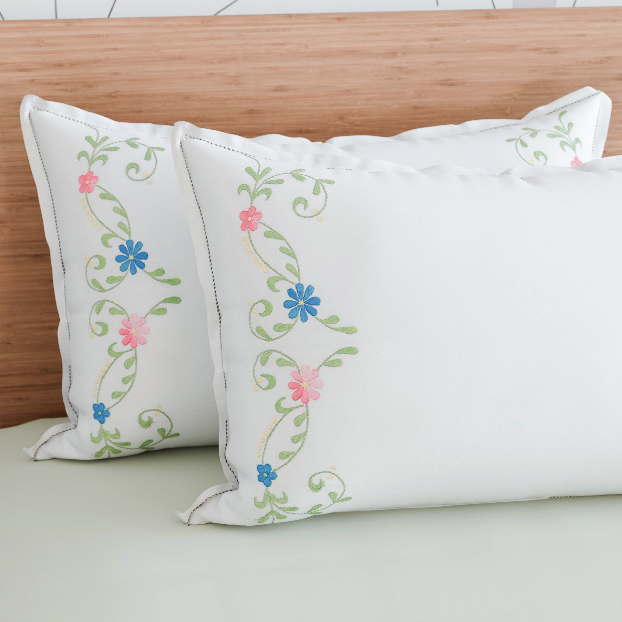 Multicoloured floral vine embroidered pillow cases styled on a bed for vibrant and elegant bedroom decor