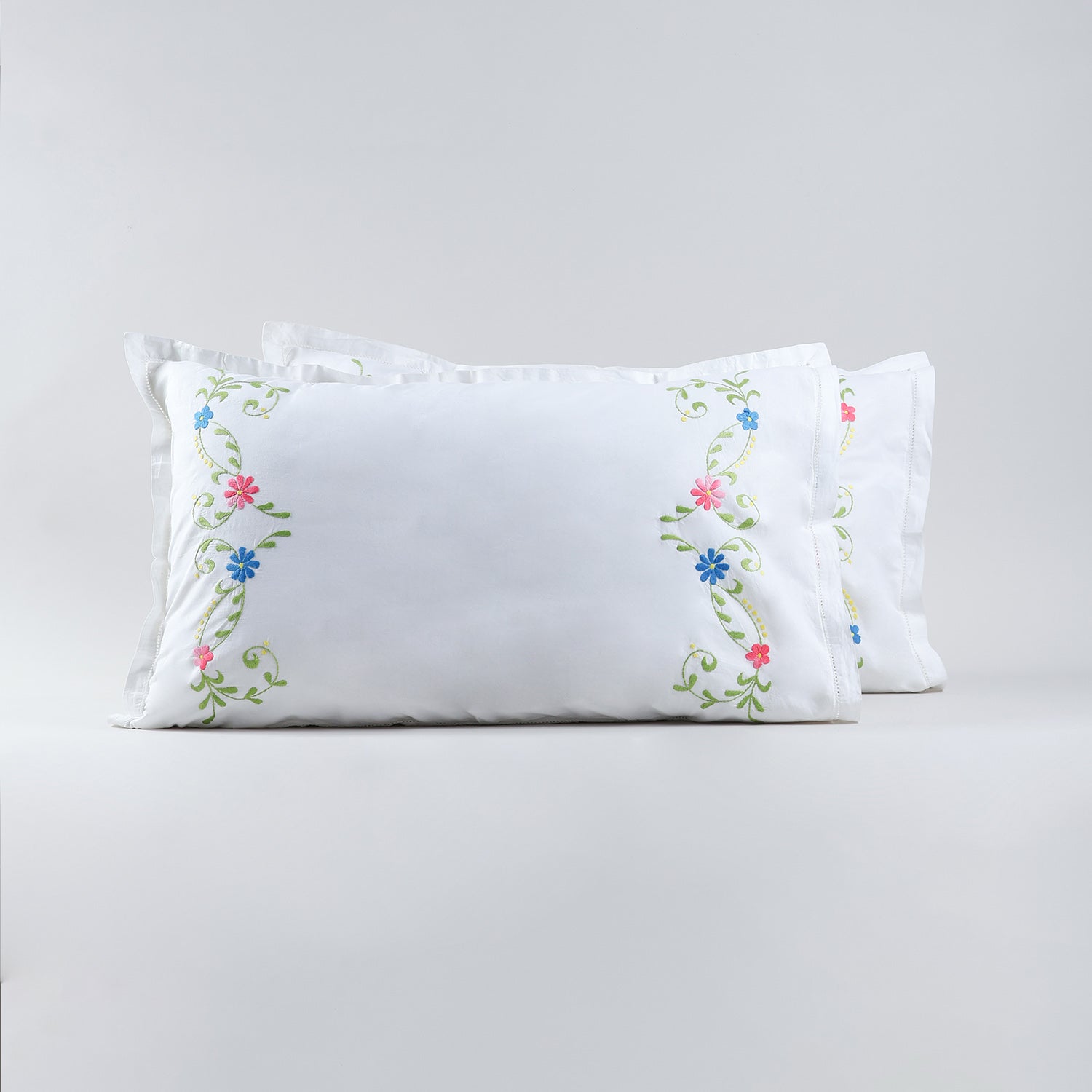 Set of two white cotton pillow cases featuring blue pink floral embroidery with green vine detailing