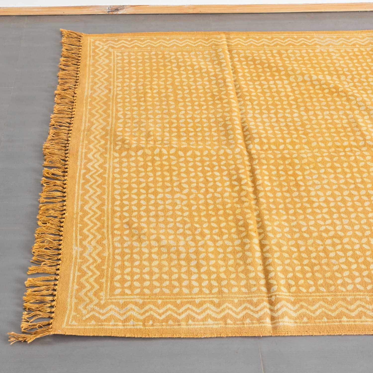 Top view of a mustard handloom cotton dhurrie featuring geometric block print patterns and decorative fringe detailing