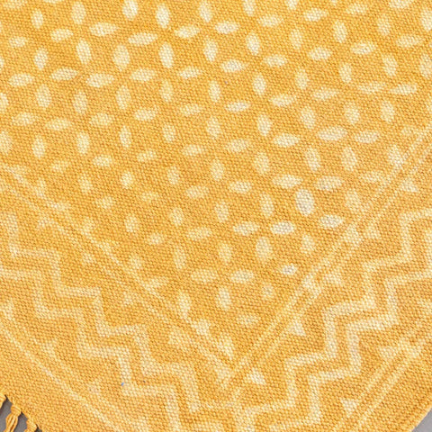 Close-up of geometric hand block printed motifs on a mustard cotton dhurrie, highlighting artisan craftsmanship and texture