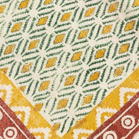 Close-up of geometric hand block printed motifs on a mustard and red cotton dhurrie highlighting artisan craftsmanship