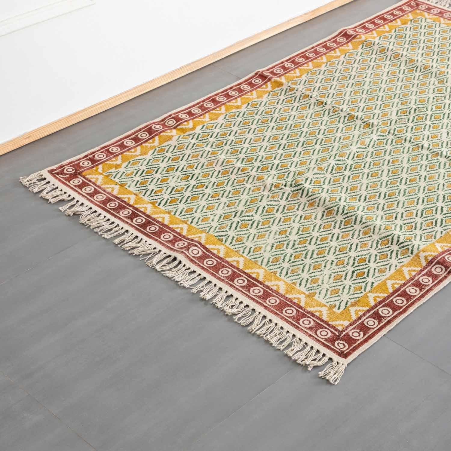 Oblique high-angle view of a mustard and red geometric block printed dhurrie rug showcasing pattern placement and craftsmanship