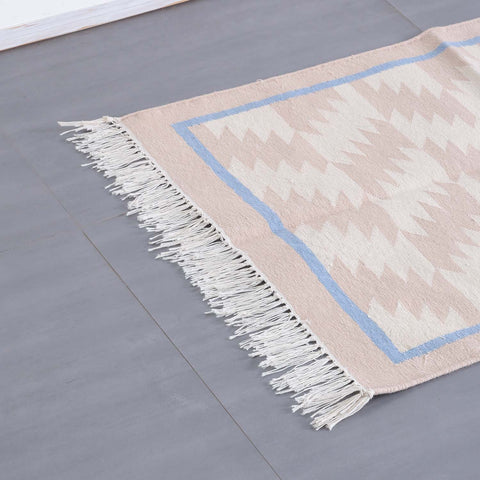 Detailed corner view of a geometric cotton dhurrie highlighting intricate weaving and neutral colour tones