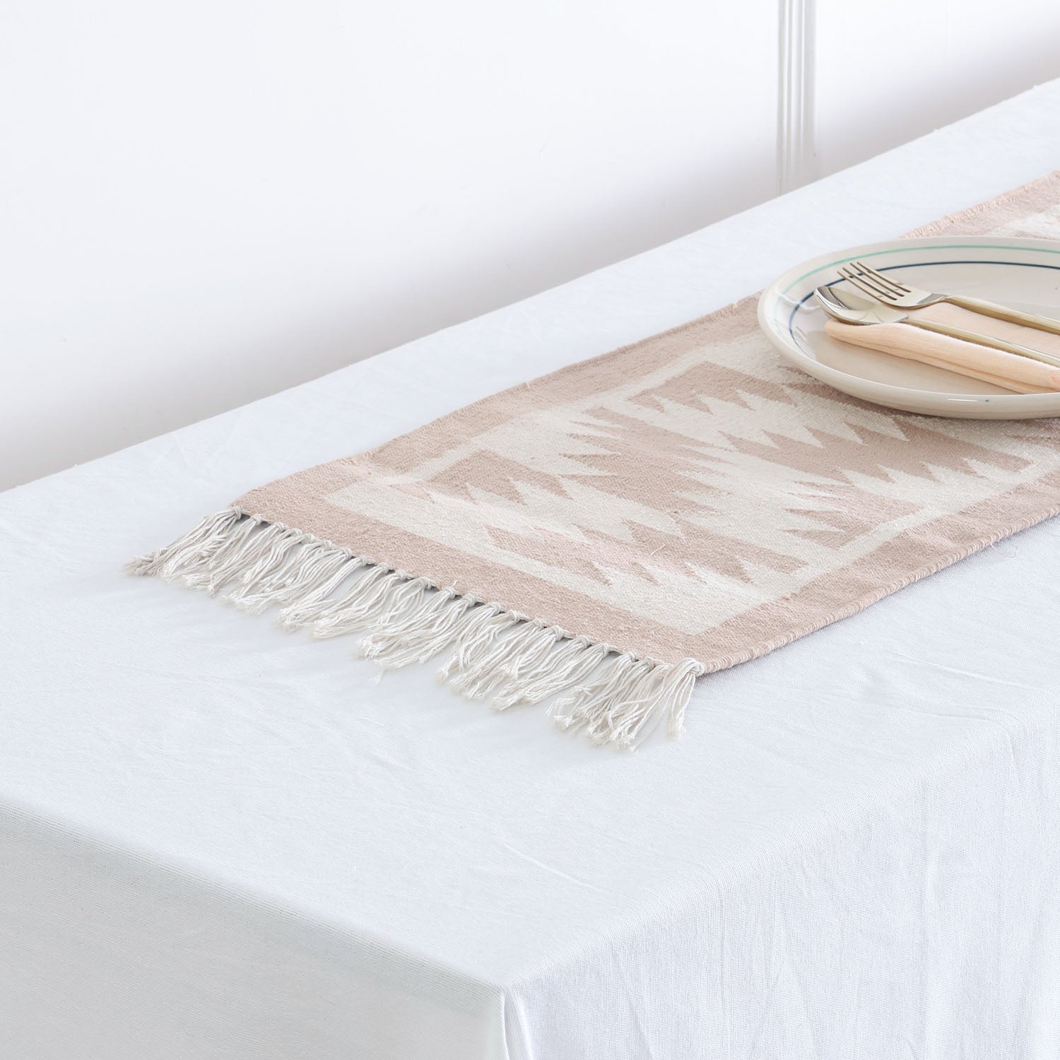 Angled view of a neutral geometric cotton floor runner styled on a table, adding texture and handcrafted elegance