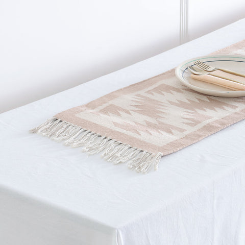 Angled view of a neutral geometric cotton floor runner styled on a table, adding texture and handcrafted elegance