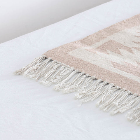 Close-up of tasseled fringe of a geometric zigzag patterns and textured handwoven cotton weave on a Bikaner dhurrie runner