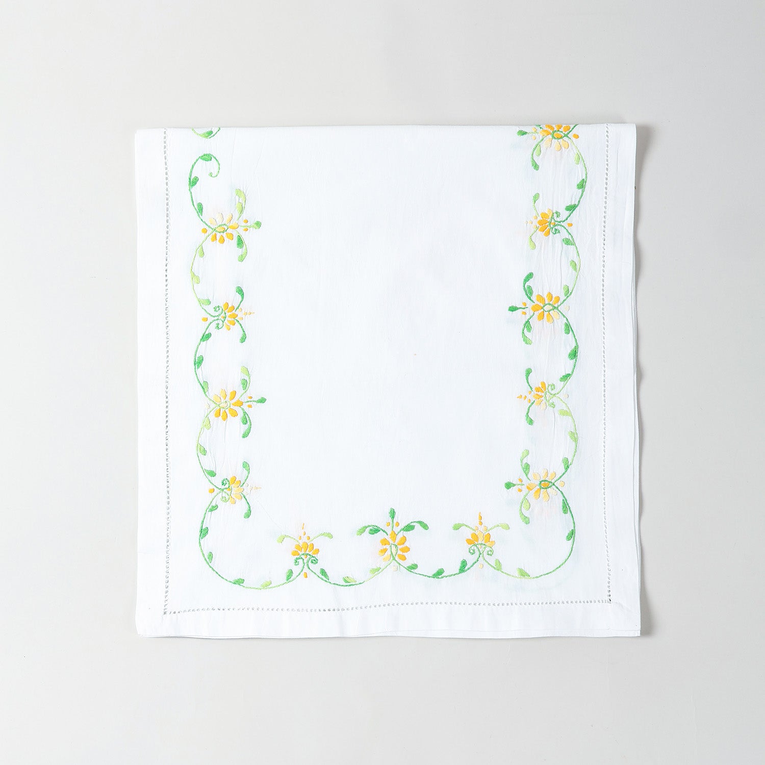 Folded white cotton table runner showcasing orange and green floral embroidery and handcrafted Bengal chikankari detailing