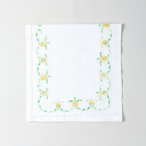 Folded white cotton table runner showcasing orange and green floral embroidery and handcrafted Bengal chikankari detailing