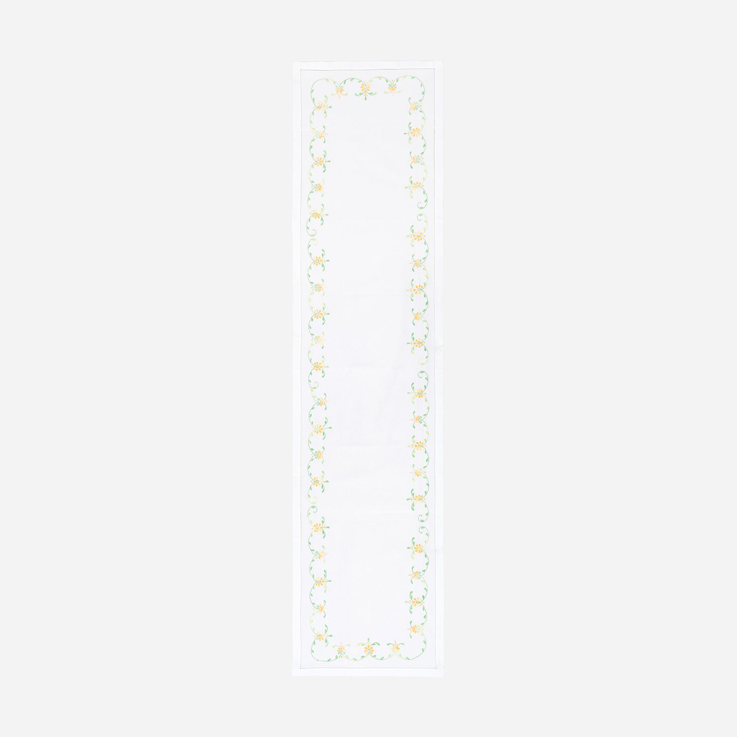 Full-length embroidered table runner featuring orange and green floral vine motifs on a white cotton base displayed on a plain background