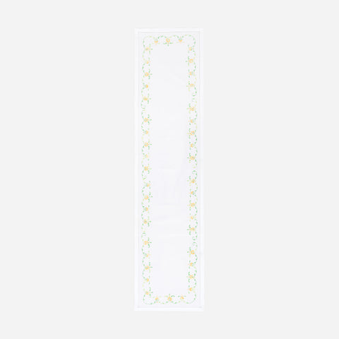 Full-length embroidered table runner featuring orange and green floral vine motifs on a white cotton base displayed on a plain background